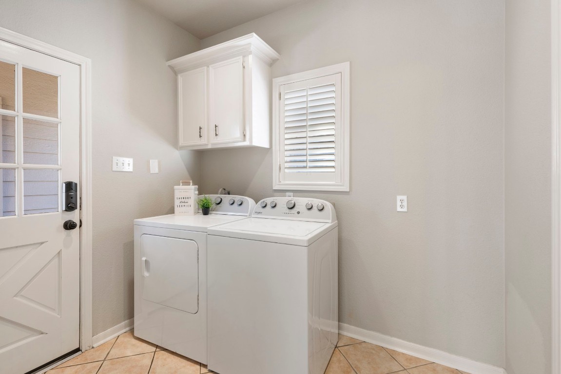 25722 Overlake Drive Spring, TX 77380 - Photo 35 of 50 The bright laundry room includes a newer washer and dryer that will be conveyed, white built-in cabinets, tile floors, and access to the backyard and detached garage, with extra space for a freezer, shelving, or whatever suits your needs to the right.