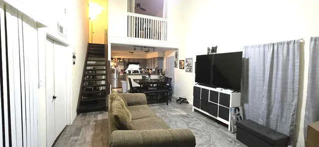 a living room with furniture a flat screen tv and a refrigerator