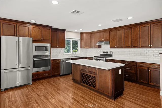 a large kitchen with stainless steel appliances wooden floors and wooden cabinets