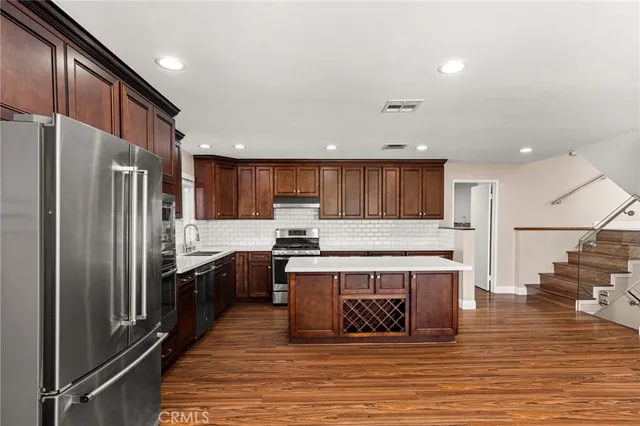a kitchen with stainless steel appliances a sink dishwasher stove refrigerator and cabinets