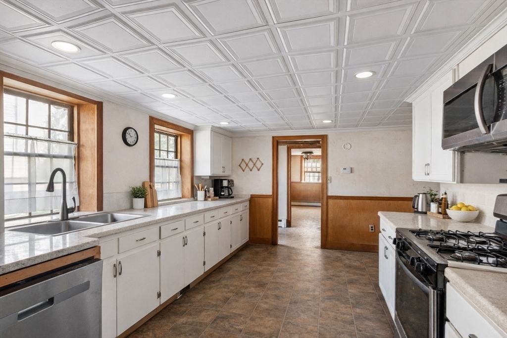4 Townsend Street Pepperell, MA 01463 - Photo 9 of 27 a large kitchen with stainless steel appliances granite countertop a large stove a sink dishwasher and white cabinets with wooden floor