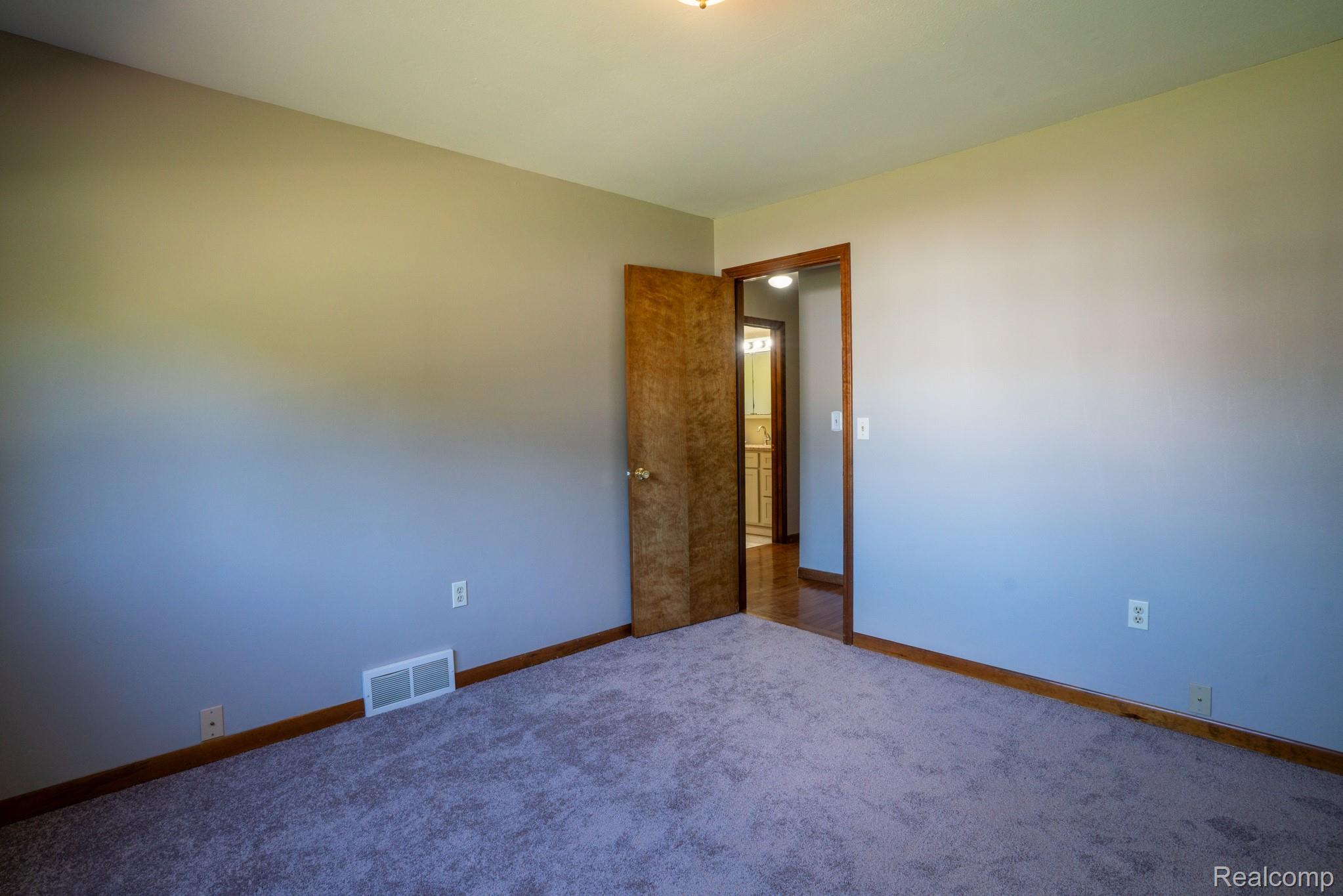 12900 Maxwell Road Carleton, MI 48117 - Photo 50 of 59 Wall-to-wall carpeting and wood-finish trim, with a wood-panel door