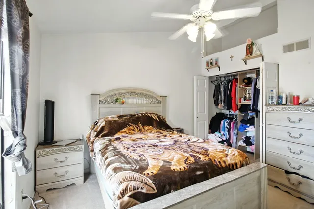 a bedroom with a bed and a flat tv screen on dresser