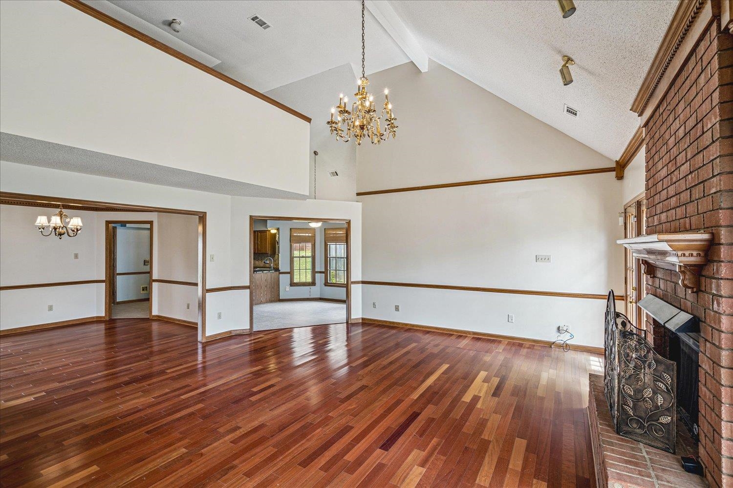 8529 Buckhurst Road Memphis, TN 38016 - Photo 12 of 36 Unfurnished living room featuring hanging lights, a fireplace, and dark wood finished floors