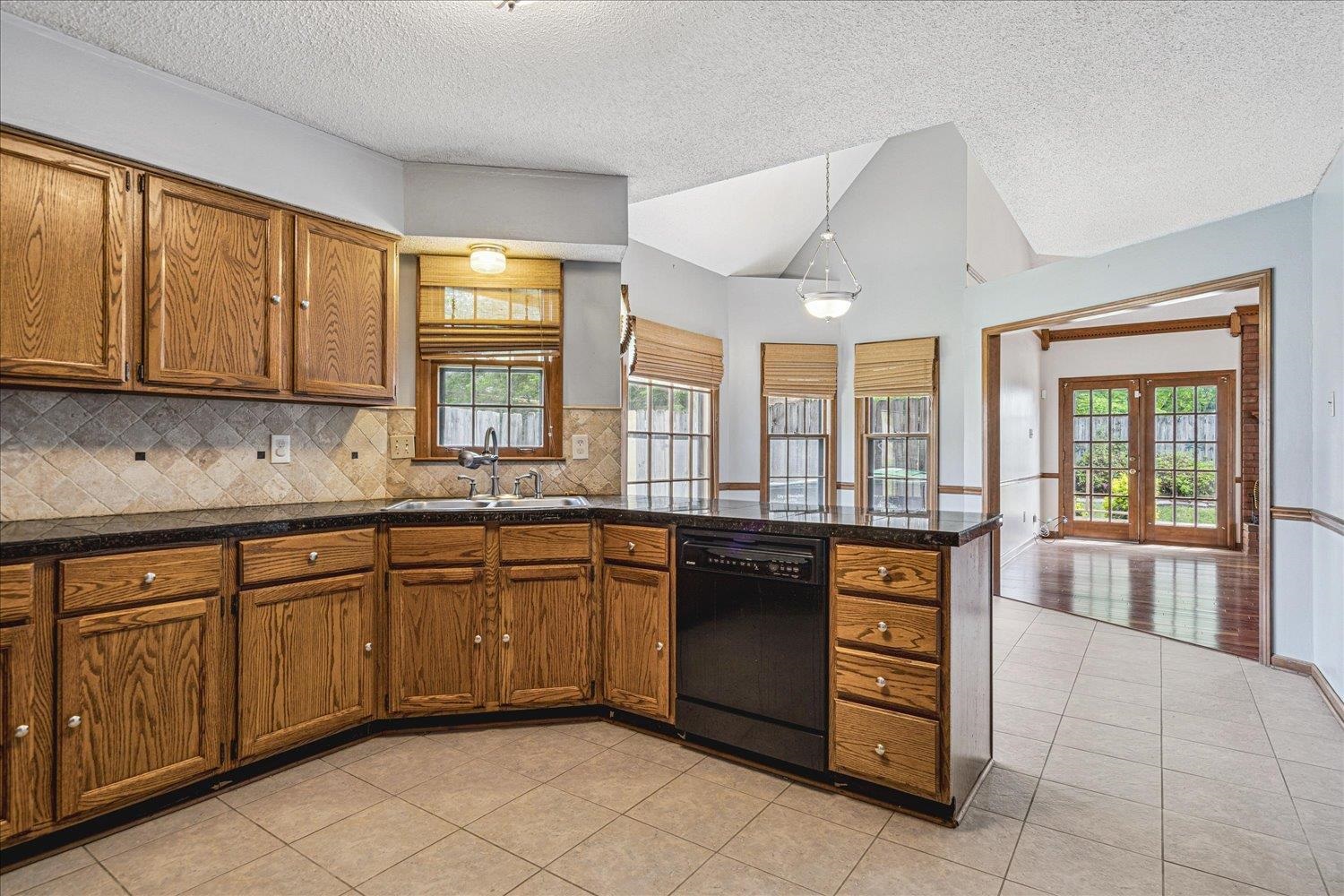 8529 Buckhurst Road Memphis, TN 38016 - Photo 14 of 36 Kitchen with light tile patterned floors, black dishwasher, hanging light fixtures, and wood finish cabinetry