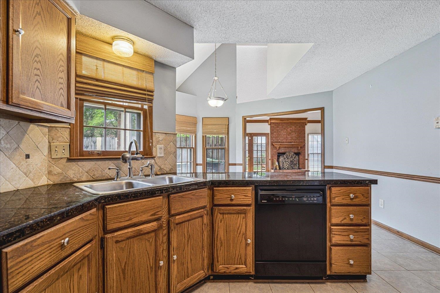 8529 Buckhurst Road Memphis, TN 38016 - Photo 15 of 36 Kitchen featuring tile countertops, black dishwasher, wood finish cabinetry, a peninsula, and tasteful backsplash