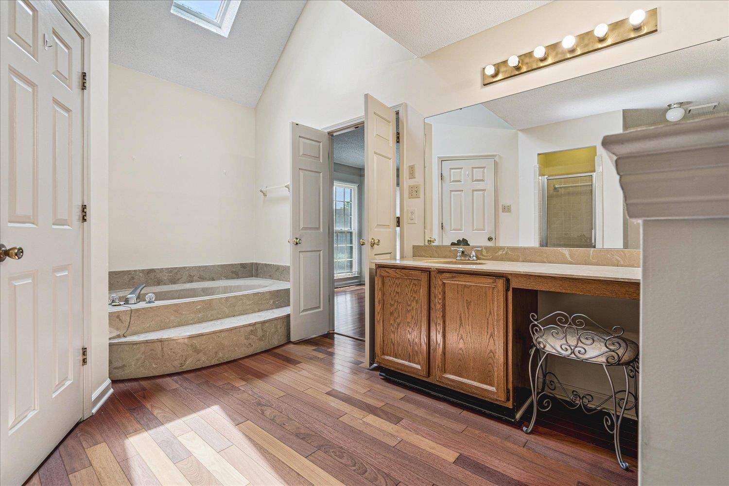 8529 Buckhurst Road Memphis, TN 38016 - Photo 21 of 36 Bathroom with a skylight, vanity, a bath, a shower stall, and light wood-type flooring