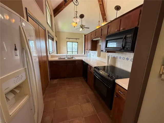 an empty room with wooden floor chandelier fan and windows