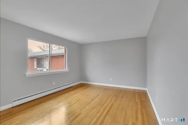 a view of an empty room with wooden floor and a window