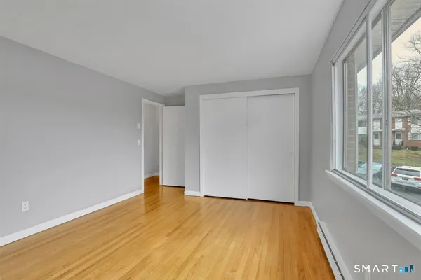 a view of empty room with wooden floor and fan