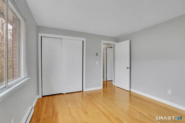 a view of an empty room with wooden floor and a window