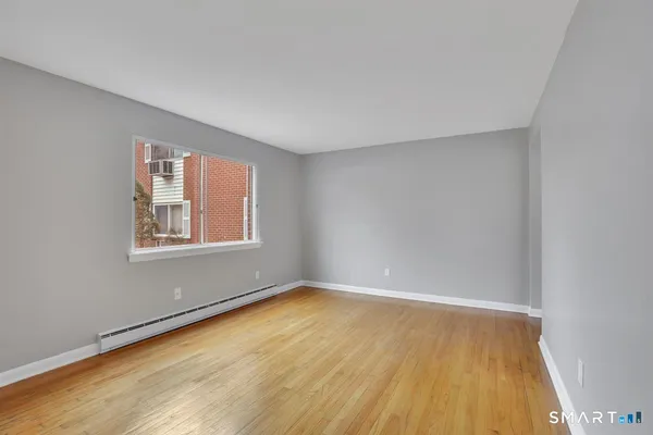 a view of an empty room with wooden floor and a window