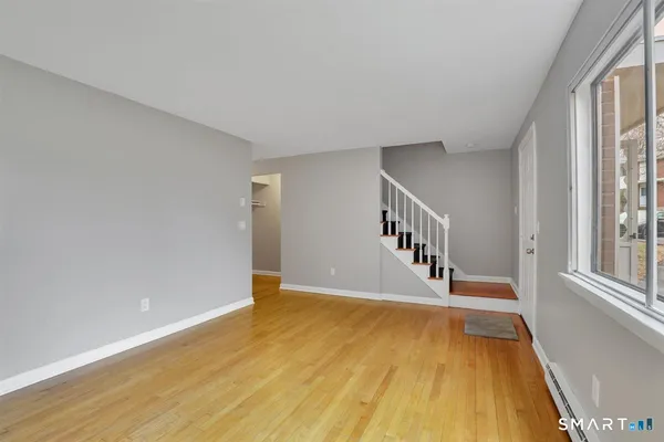 a view of an empty room with wooden floor and a window