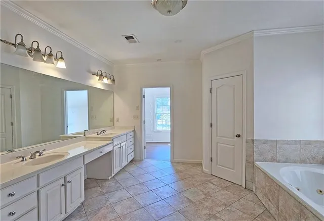 a large bathroom with a granite countertop double vanity sink a mirror and a bathtub
