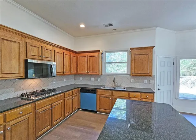 a kitchen with granite countertop stainless steel appliances stove sink and cabinets