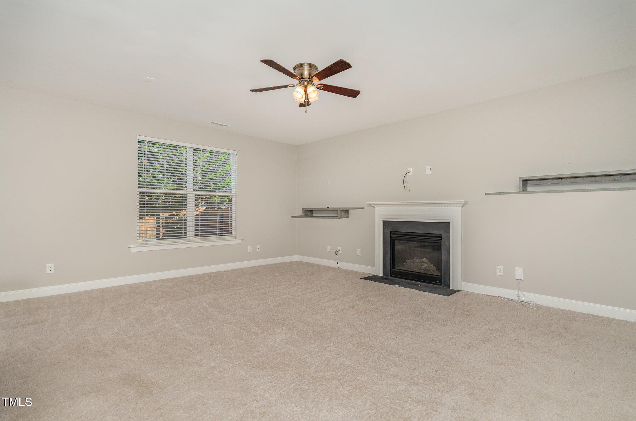 3529 Eastern Branch Road Raleigh, NC 27610 - Photo 5 of 29 an empty room with windows fireplace and ceiling fan