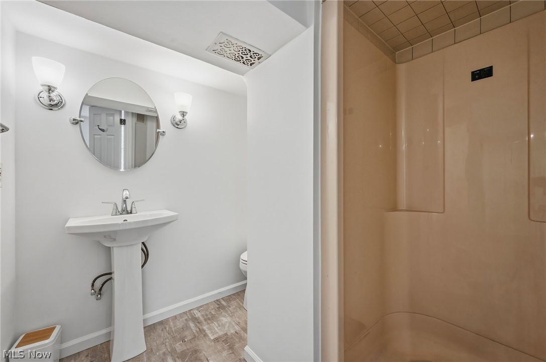 7750 Lewis Road Olmsted Falls, OH 44138 - Photo 36 of 50 Pedestal sink with chrome fixtures, illuminated by two wall sconces flanking a circular mirror