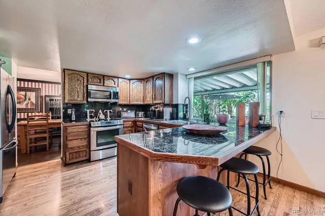 a kitchen with stainless steel appliances granite countertop a stove a refrigerator a kitchen island a table and chairs