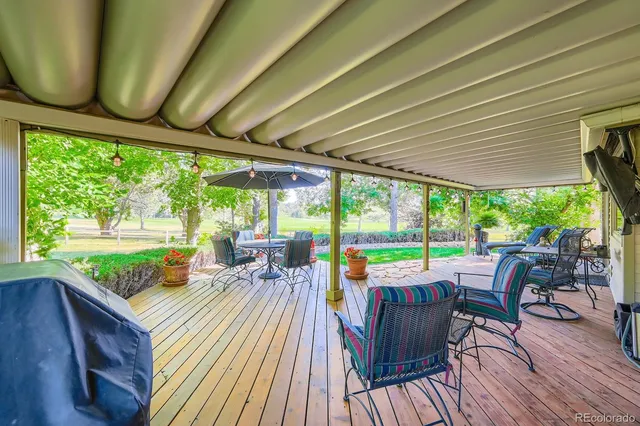 a view of a patio with table and chairs potted plants with wooden floor and garden view