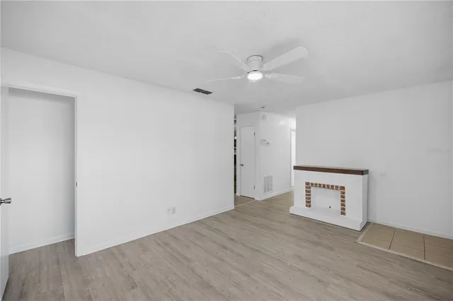 an empty room with wooden floor and ceiling fan