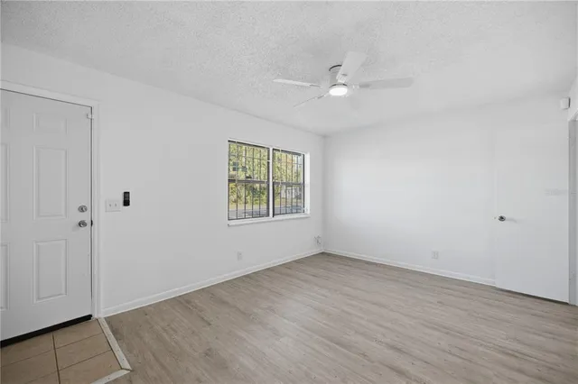 an empty room with wooden floor closet and windows