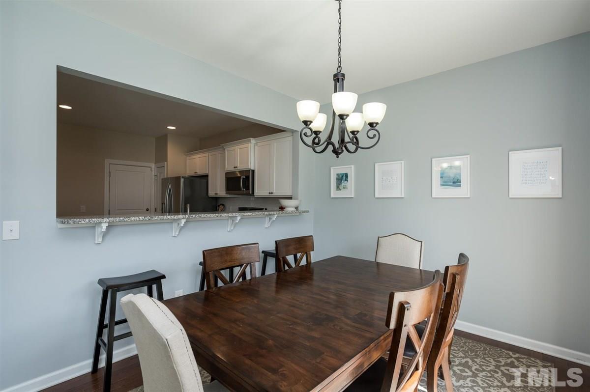 8705 Wild Magnolia Drive Raleigh, NC 27617 - Photo 6 of 15 a view of a dining room with furniture a chandelier and wooden floor