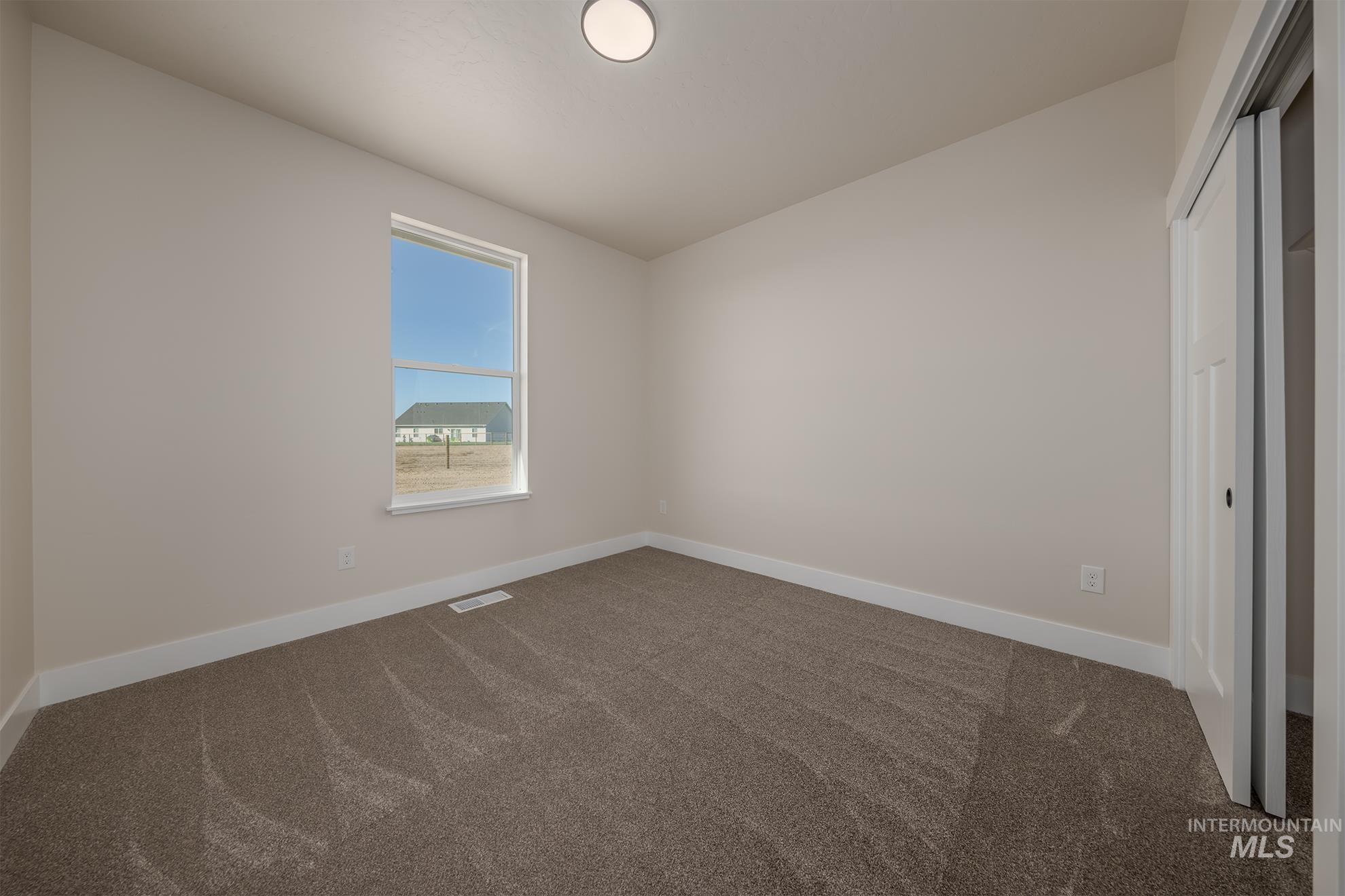 1371 Hansen Road Weiser, ID 83672 - Photo 27 of 44 Neutral-toned walls, carpet flooring, a single window, and a built-in closet with bi-fold doors