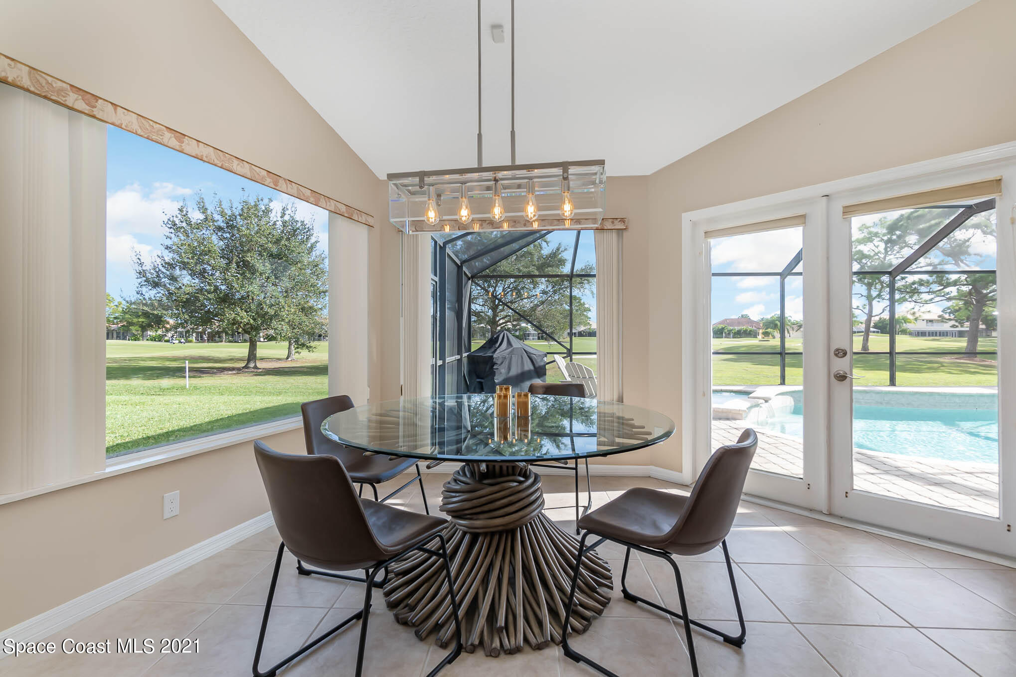 689 Spring Lake Drive Melbourne, FL 32940 - Photo 11 of 49 a dining room with furniture large windows and a chandelier