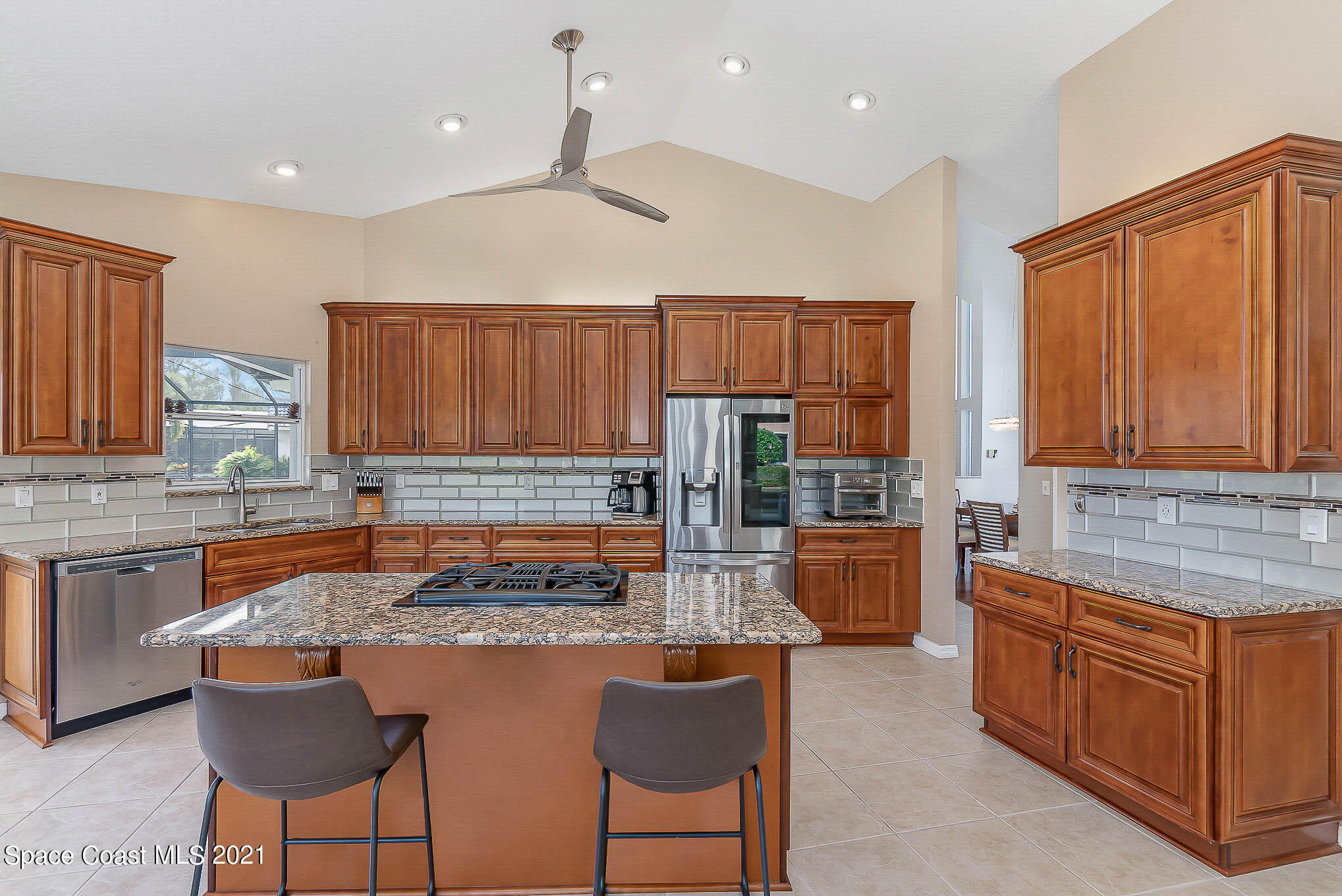 689 Spring Lake Drive Melbourne, FL 32940 - Photo 12 of 49 a kitchen with kitchen island granite countertop wooden cabinets and a refrigerator