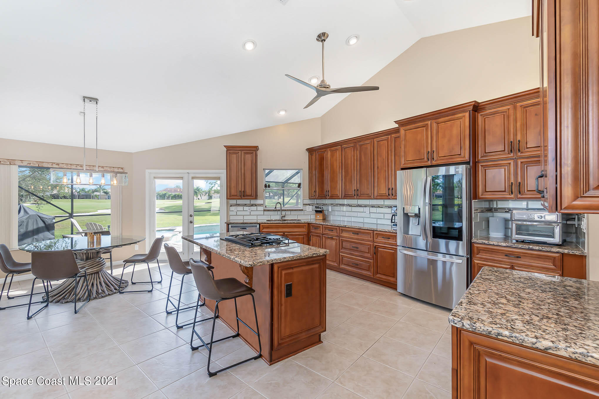 689 Spring Lake Drive Melbourne, FL 32940 - Photo 14 of 49 a kitchen with stainless steel appliances granite countertop a stove oven and a refrigerator with wooden cabinets