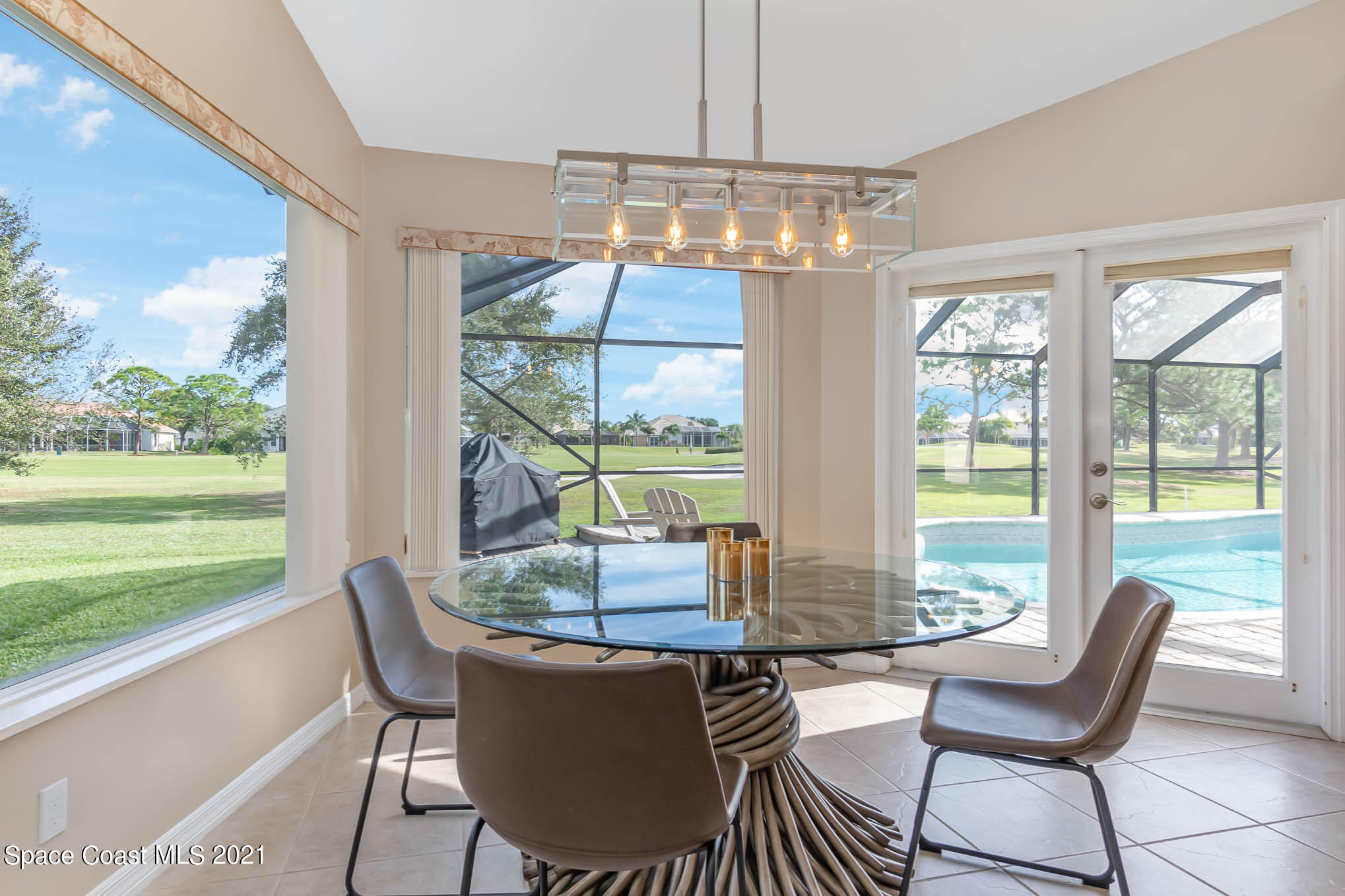 689 Spring Lake Drive Melbourne, FL 32940 - Photo 10 of 49 a dining room with furniture a chandelier and garden view