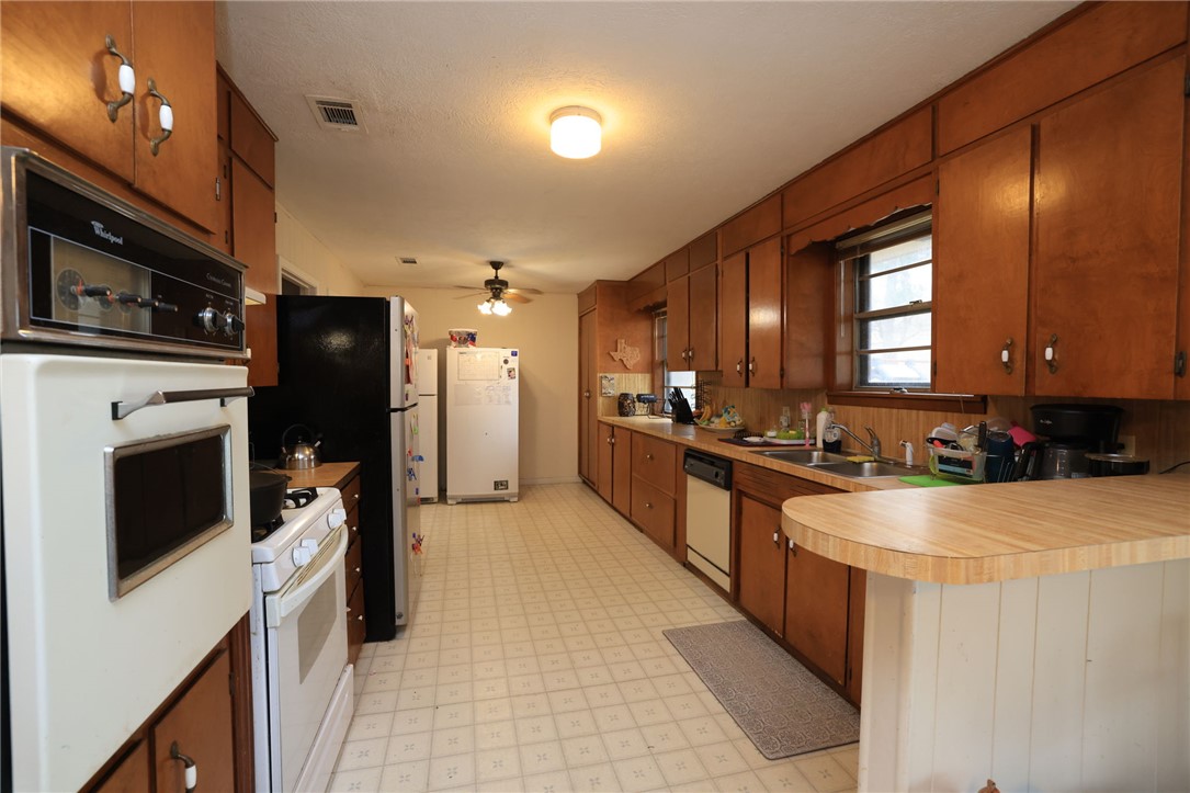 7474 Welch Road Bryan, TX 77808 - Photo 9 of 27 a large kitchen with stainless steel appliances kitchen island granite countertop a refrigerator a stove top oven and a sink with wooden floor