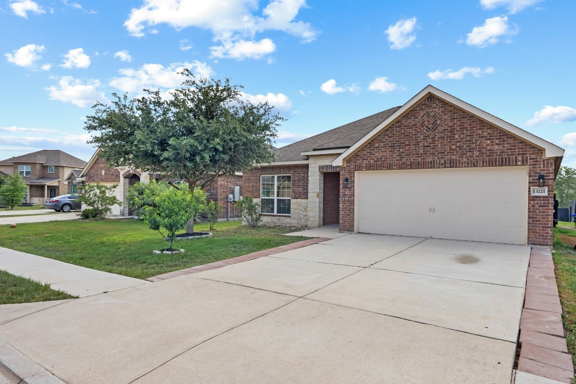 13221 Cabinet Drive Manor, TX 78653 - Photo 1 of 1 View of front of house with brick siding, an attached garage, a front yard, concrete driveway, and roof with shingles