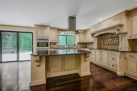 a kitchen with granite countertop a stove a sink and white cabinets with wooden floor