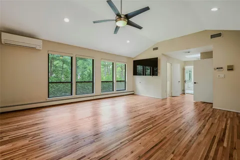 a view of empty room with wooden floor and fan