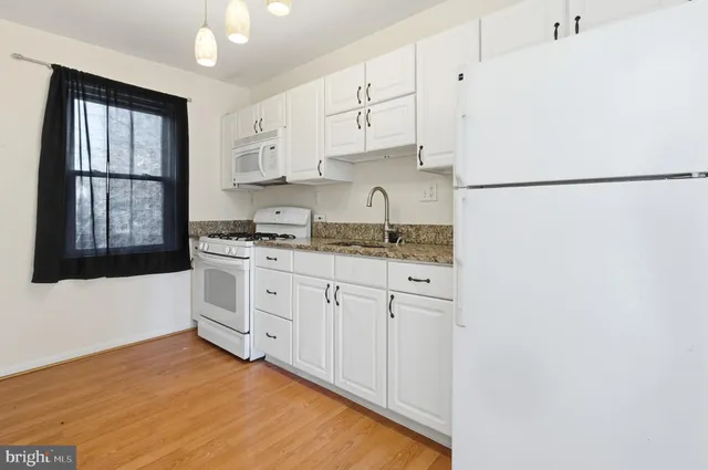 a kitchen with granite countertop white cabinets and white appliances