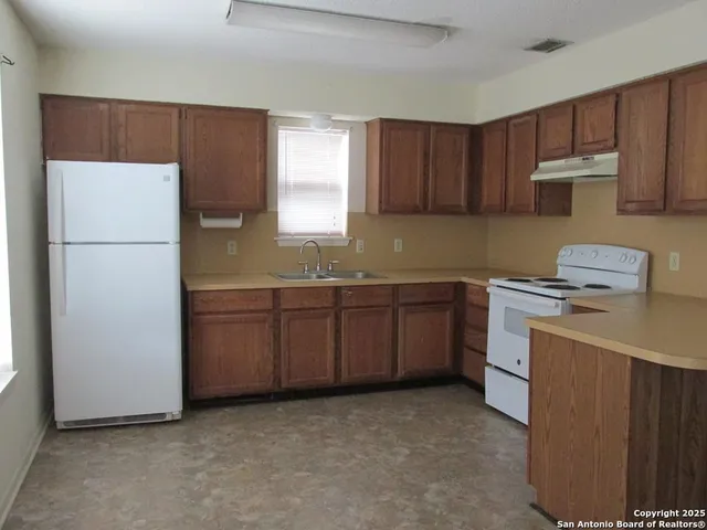 a kitchen with sink a refrigerator and cabinets
