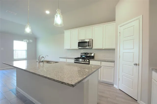 a kitchen with sink a microwave and cabinets