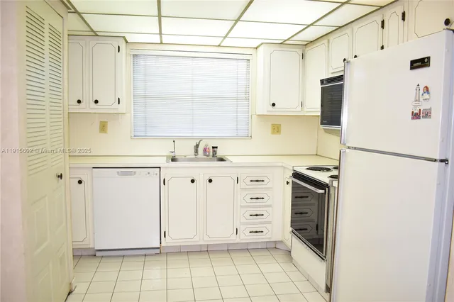 a kitchen with granite countertop white cabinets and white appliances