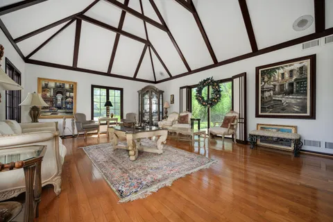 a living room with furniture a large window and wooden floor