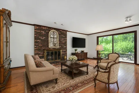 a living room with furniture a flat screen tv and floor to ceiling window