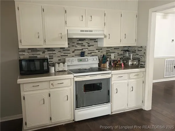 a kitchen with granite countertop white cabinets and white appliances