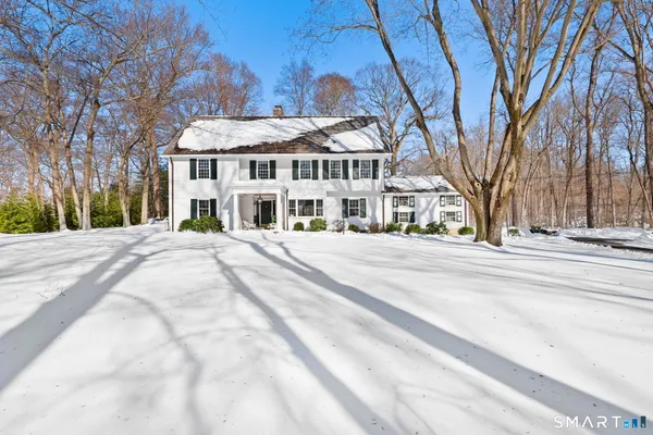 a view of a white house with a yard covered in snow