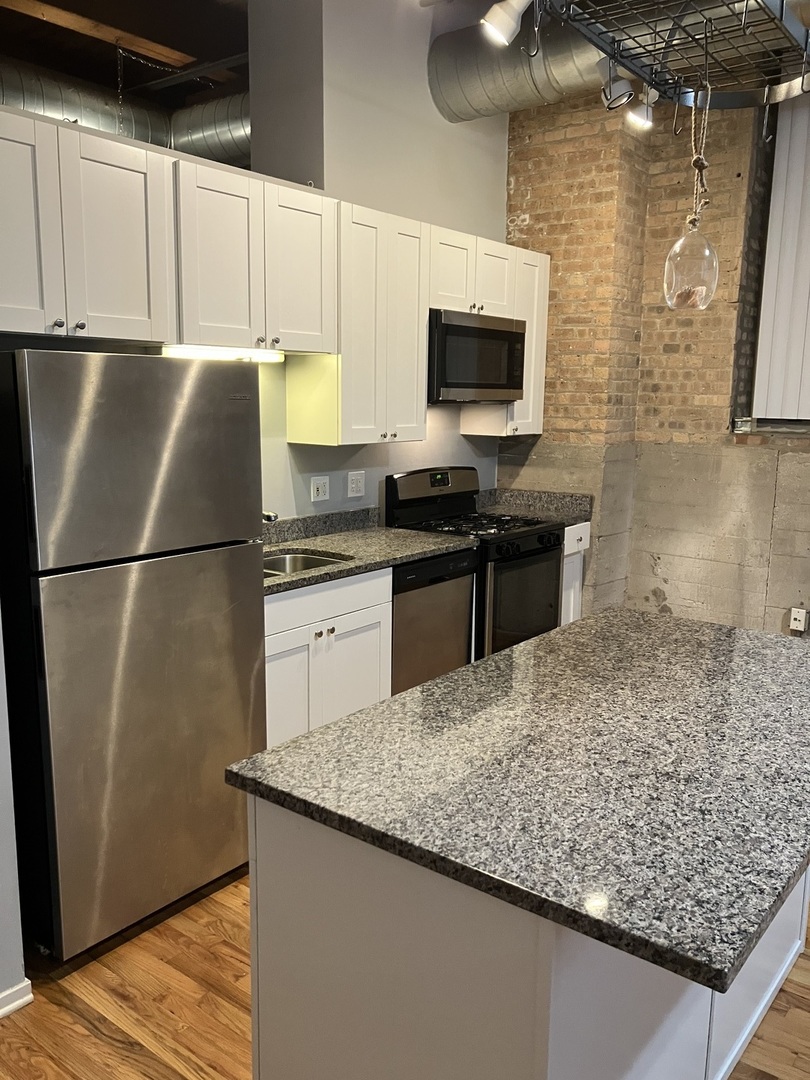 1500 West Monroe Street, Unit 113 Chicago, IL 60607 - Photo 4 of 15 a kitchen with stainless steel appliances granite countertop a sink stove and refrigerator