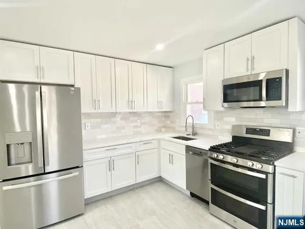 a kitchen with white cabinets sink and stainless steel appliances