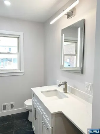 a bathroom with a sink toilet vanity and window