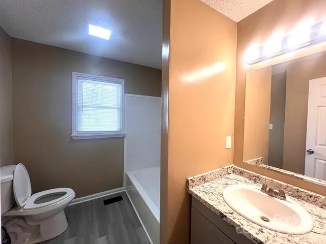 a bathroom with a granite countertop sink toilet and shower