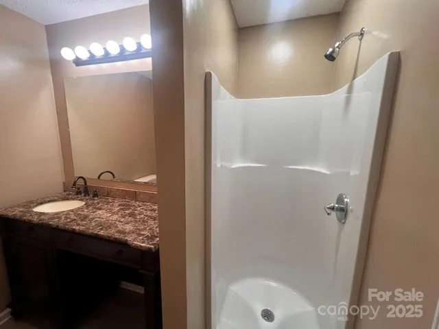 a bathroom with a granite countertop sink a mirror and shower