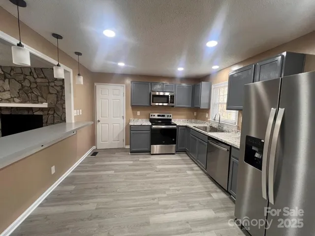 a large kitchen with stainless steel appliances granite countertop a refrigerator and a stove top oven