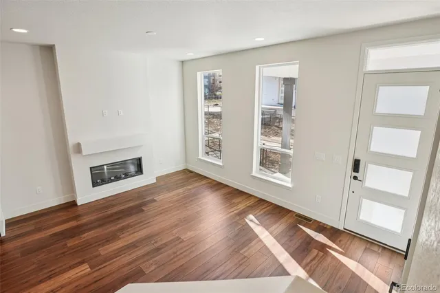 a view of an empty room with wooden floor and a window